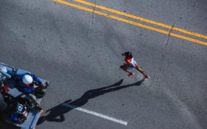 a helicopter view picture of someone running and a video team filming her