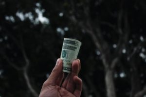 a hand with a roll of 20 dollar bills